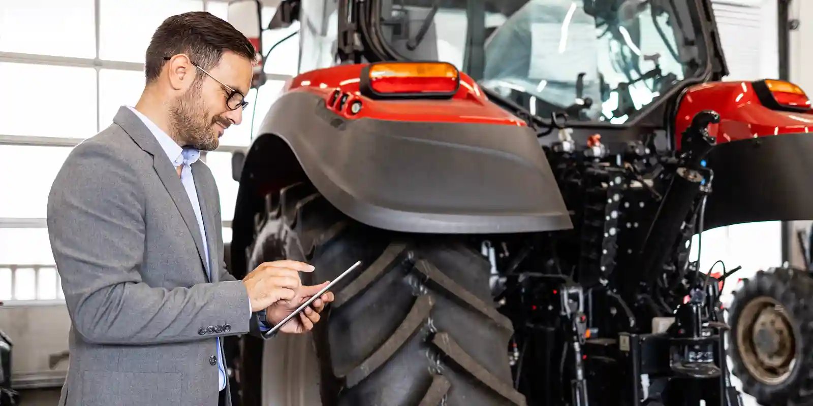 Equipment service professional reviewing information on a tablet beside tractors
